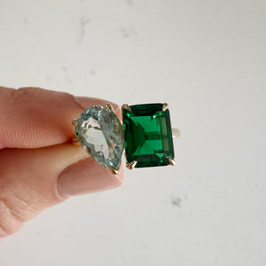 Toi et Moi ring with an emerald-cut Emerald and a pear-cut Aquamarine.