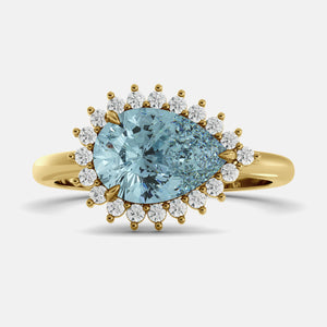Gold ring with a large blue gemstone and smaller diamonds on a light gray background