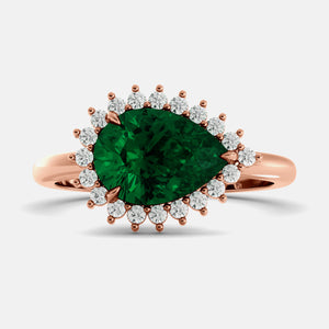 Rose gold ring with a large green gemstone and smaller diamonds on a light gray background