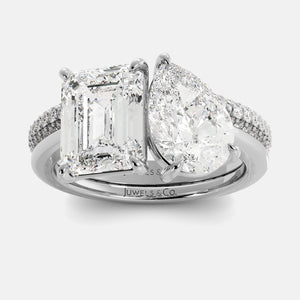 Diamond ring with emerald-cut and pear-shaped gemstones on a white background
