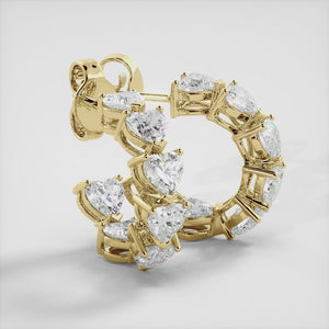 A pair of heart-shaped diamond hoop earrings in recycled yellow gold. The earrings are made of recycled yellow gold and have a simple, elegant design. The hoops are approximately 1 inch in diameter and are set with heart-shaped diamonds. The diamonds are sparkling and reflect light beautifully. The earrings are a perfect gift for a loved one or a special occasion.