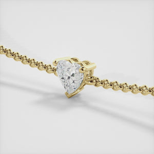 A close-up of a heart-shaped diamond bracelet in recycled yellow gold. The bracelet is set with a single, large diamond in the center of a heart-shaped pendant. The bracelet is made of recycled yellow gold and has a simple, elegant design. The diamond is sparkling and reflects light beautifully. The bracelet is a perfect gift for a loved one or a special occasion.