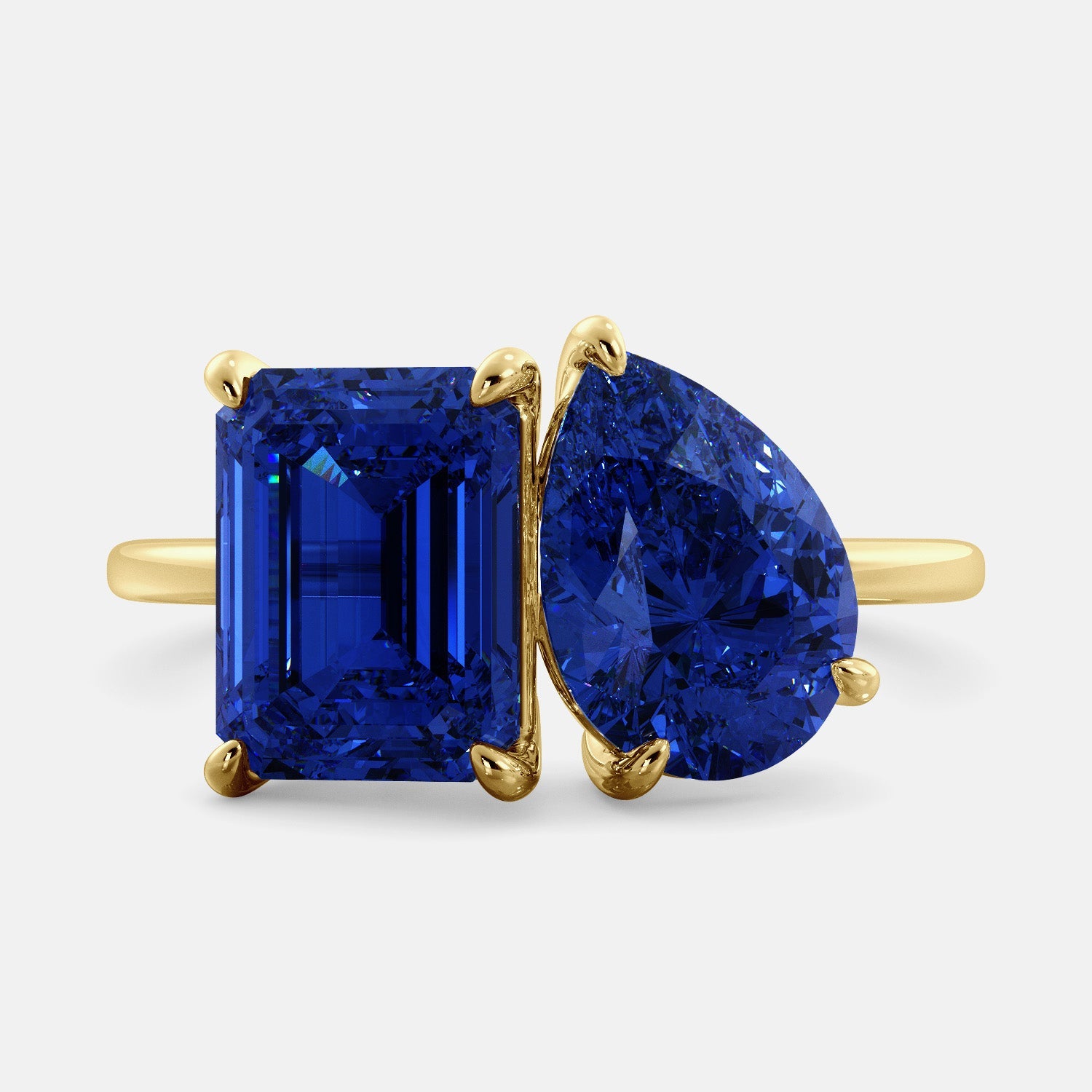 A toi et moi ring with an emerald-cut Blue Sapphire and pear-cut gemstone. The emerald-cut morganite is set on the left of the ring, and the pear-cut gemstone is set on the right. The ring is made of recycled yellow gold and has a simple, elegant design. The pear-cut gemstone can be customized. **Here are some additional details about the image:** * The emerald-cut white Blue Sapphire is a birthstone for September. * The pear-cut gemstone can be customized to any stone of your choice.