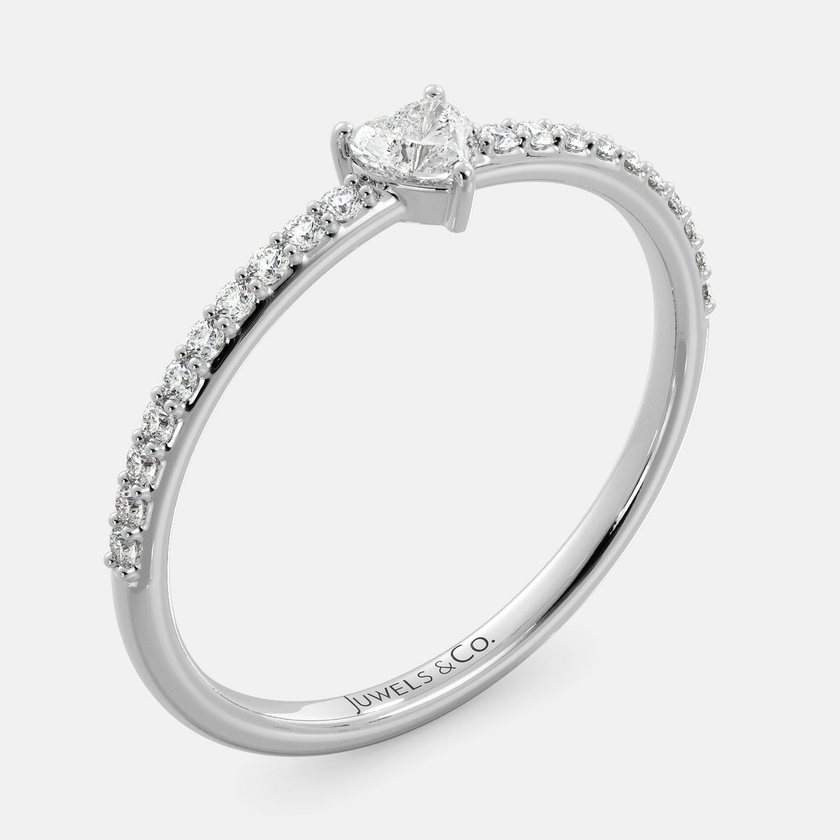 A close-up of a heart-shaped diamond ring with side stones in recycled white gold. The ring is set with a single, large diamond in the center of a heart-shaped setting. The ring is made of recycled yellow gold and has a simple, elegant design. The diamond is sparkling and reflects light beautifully. The side stones are smaller diamonds that are set in the band of the ring. The ring is a perfect gift for a loved one or a special occasion.