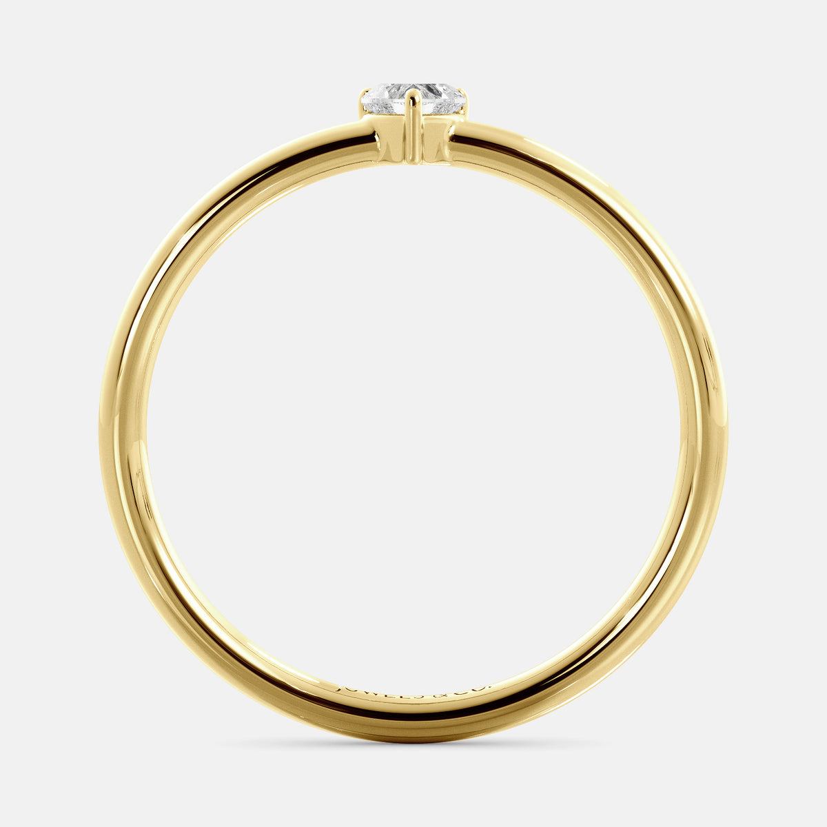 A close-up of a heart-shaped solitaire diamond ring in recycled yellow gold. The ring is set with a single, large diamond in the center of a heart-shaped setting. The ring is made of recycled yellow gold and has a simple, elegant design. The diamond is sparkling and reflects light beautifully. The ring is a perfect gift for a loved one or a special occasion.