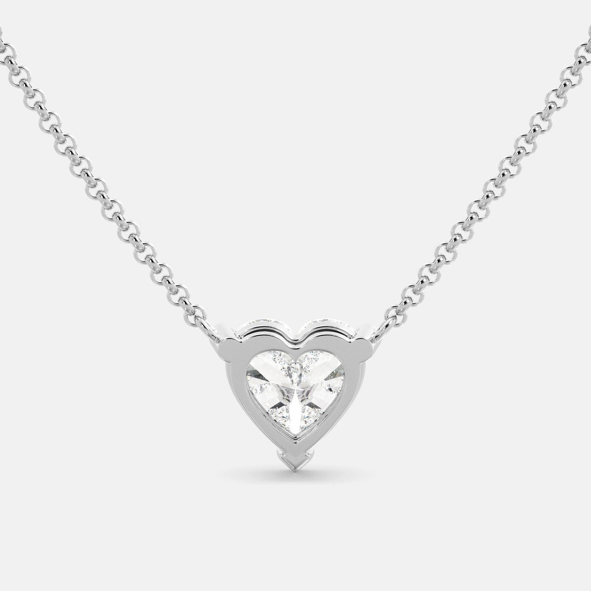 A close-up of a heart-shaped diamond necklace in recycled white gold. The necklace is set with a single heart-shaped diamond in the center of a pendant. The necklace is made of recycled white gold and has a simple, elegant design. The diamond is sparkling and reflects light beautifully. The necklace is a perfect gift for a loved one or a special occasion.