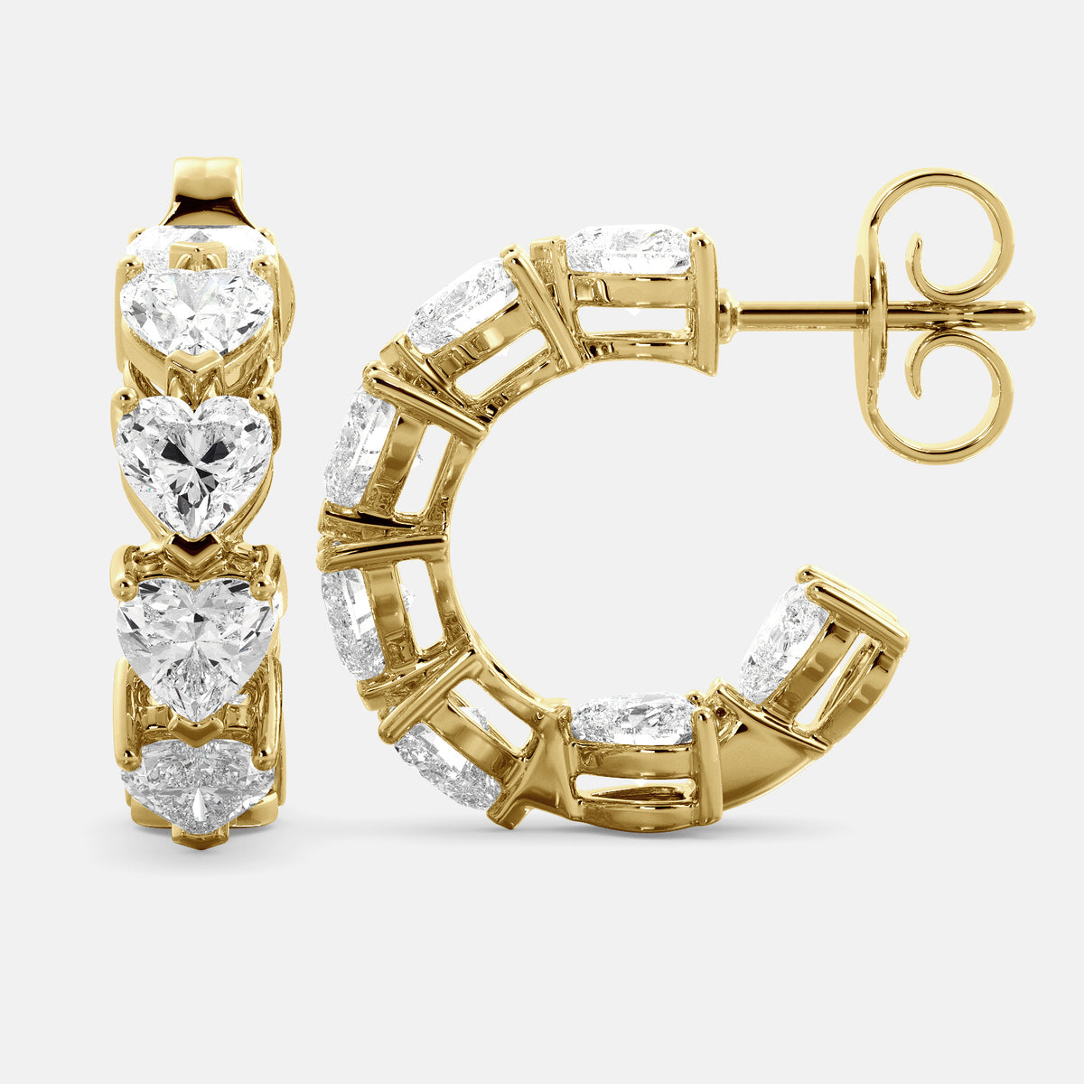 A pair of heart-shaped diamond hoop earrings in recycled yellow gold. The earrings are made of recycled yellow gold and have a simple, elegant design. The hoops are approximately 1 inch in diameter and are set with heart-shaped diamonds. The diamonds are sparkling and reflect light beautifully. The earrings are a perfect gift for a loved one or a special occasion.