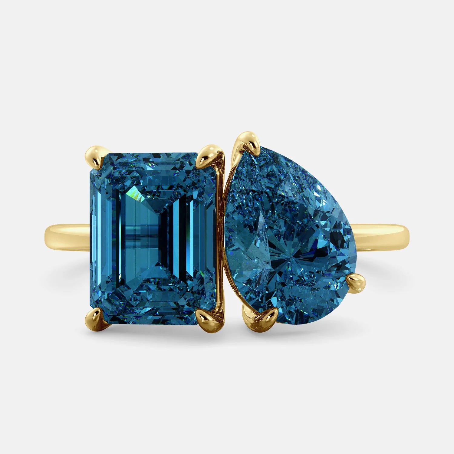A toi et moi ring with an emerald-cut London Blue Topaz and pear-cut gemstone. The emerald-cut morganite is set on the left of the ring, and the pear-cut gemstone is set on the right. The ring is made of recycled yellow gold and has a simple, elegant design. The pear-cut gemstone can be customized. **Here are some additional details about the image:** * The emerald-cut white London Blue Topaz is a birthstone for December. * The pear-cut gemstone can be customized to any stone of your choice.