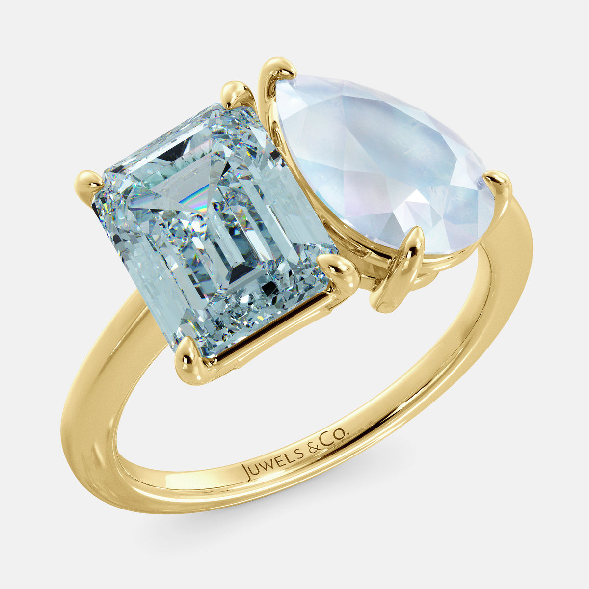 A toi et moi ring with an emerald-cut aquamarine and a pear-cut gemstone. The emerald-cut morganite is set on the left of the ring, and the pear-cut gemstone is set on the right. The ring is made of recycled yellow gold and has a simple, elegant design. The pear-cut gemstone can be customized. **Here are some additional details about the image:** * The emerald-cut aquamarine is a birthstone for March. * The pear-cut gemstone can be customized to any stone of your choice.