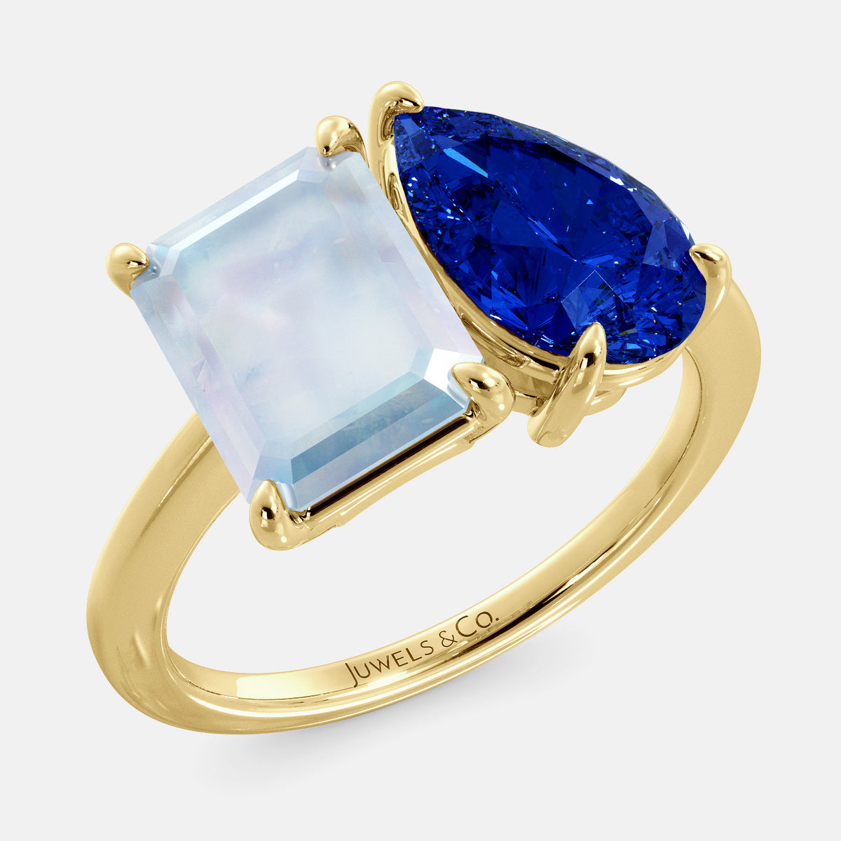 A toi et moi ring with an emerald-cut moonstone and a pear-cut gemstone. The emerald-cut morganite is set on the left of the ring, and the pear-cut gemstone is set on the right. The ring is made of recycled yellow gold and has a simple, elegant design. The pear-cut gemstone can be customized. **Here are some additional details about the image:** * The emerald-cut white moonstone is a birthstone for June. * The pear-cut gemstone can be customized to any stone of your choice.