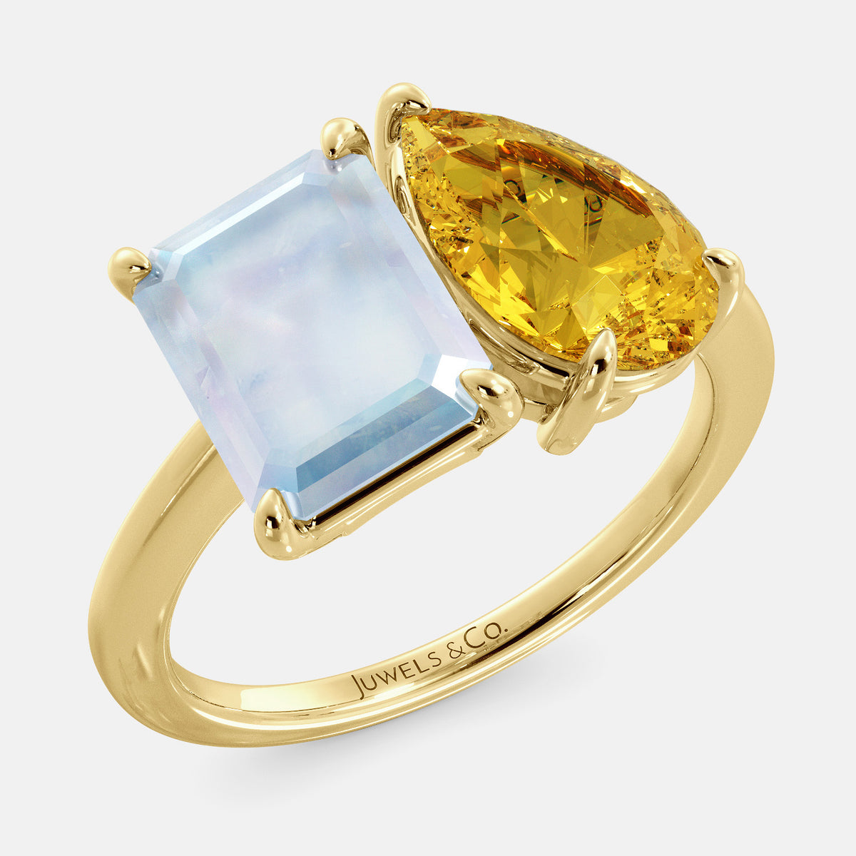 A toi et moi ring with an emerald-cut moonstone and a pear-cut gemstone. The emerald-cut morganite is set on the left of the ring, and the pear-cut gemstone is set on the right. The ring is made of recycled yellow gold and has a simple, elegant design. The pear-cut gemstone can be customized. **Here are some additional details about the image:** * The emerald-cut white moonstone is a birthstone for June. * The pear-cut gemstone can be customized to any stone of your choice.