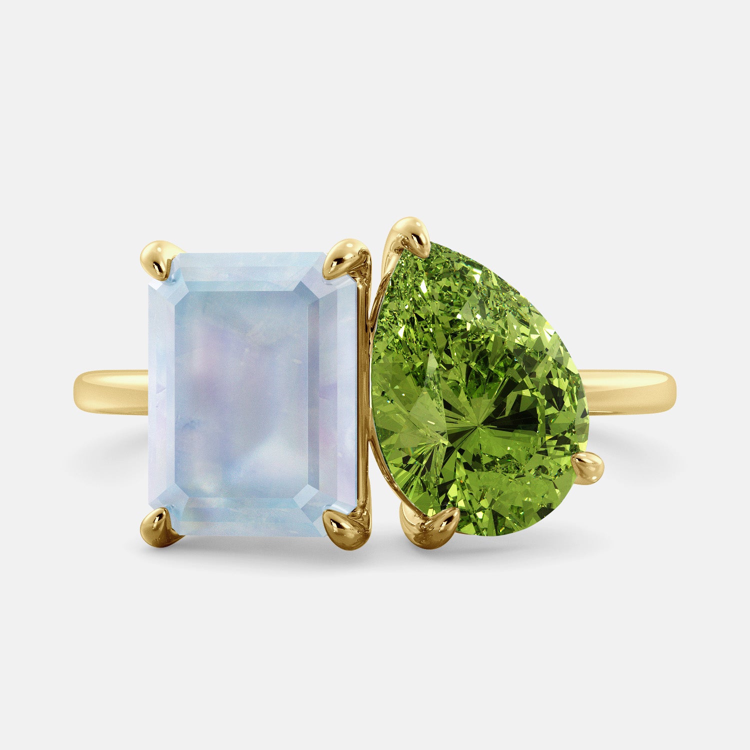 A toi et moi ring with an emerald-cut moonstone and a pear-cut gemstone. The emerald-cut morganite is set on the left of the ring, and the pear-cut gemstone is set on the right. The ring is made of recycled yellow gold and has a simple, elegant design. The pear-cut gemstone can be customized. **Here are some additional details about the image:** * The emerald-cut white moonstone is a birthstone for June. * The pear-cut gemstone can be customized to any stone of your choice.