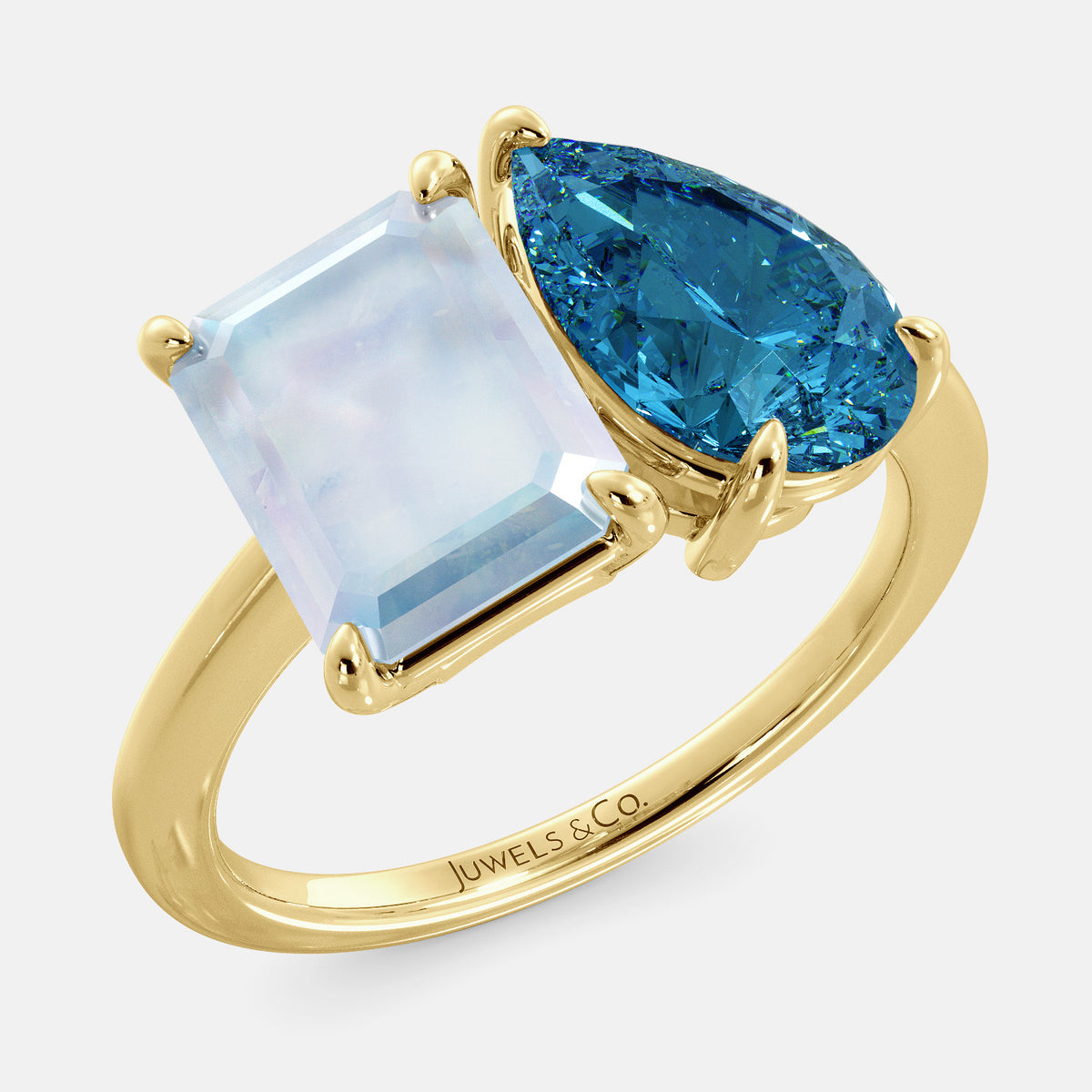 A toi et moi ring with an emerald-cut moonstone and a pear-cut gemstone. The emerald-cut morganite is set on the left of the ring, and the pear-cut gemstone is set on the right. The ring is made of recycled yellow gold and has a simple, elegant design. The pear-cut gemstone can be customized. **Here are some additional details about the image:** * The emerald-cut white moonstone is a birthstone for June. * The pear-cut gemstone can be customized to any stone of your choice.