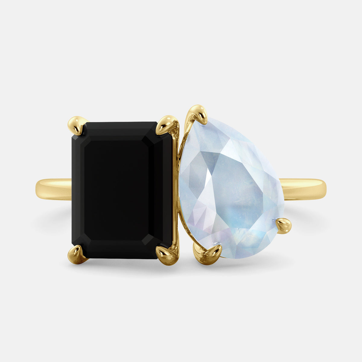 A toi et moi ring with a onyx stone in emerald cut and a pear-shaped stone. The onyx is a deep dark color and the pear-shaped stone can be customized to represent the birth month stone of the wearer or a loved one. The ring is made of 14k gold and is available in all sizes. This ring is a perfect gift for any occasion, and it can be customized to make it truly unique.