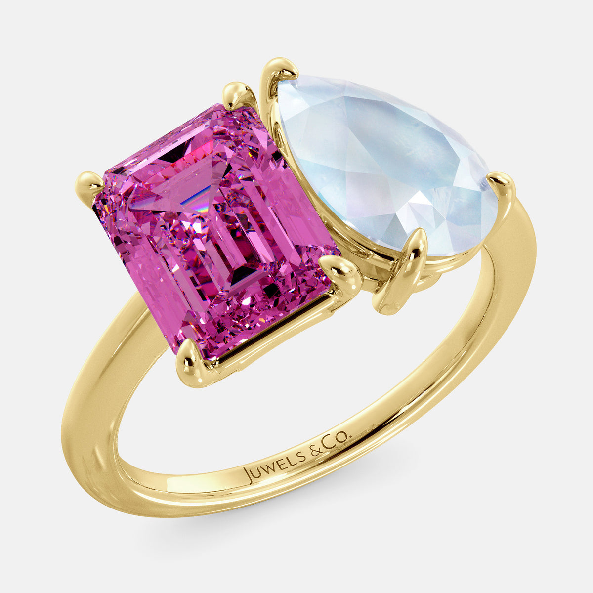 A toi et moi ring with an emerald-cut Pink Sapphire and pear-cut gemstone. The emerald-cut is set on the left of the ring, and the pear-cut gemstone is set on the right. The ring is made of recycled yellow gold and has a simple, elegant design. The pear-cut gemstone can be customized. **Here are some additional details about the image:** * The emerald-cut white Pink Sapphire is a birthstone for October. * The pear-cut gemstone can be customized to any stone of your choice.