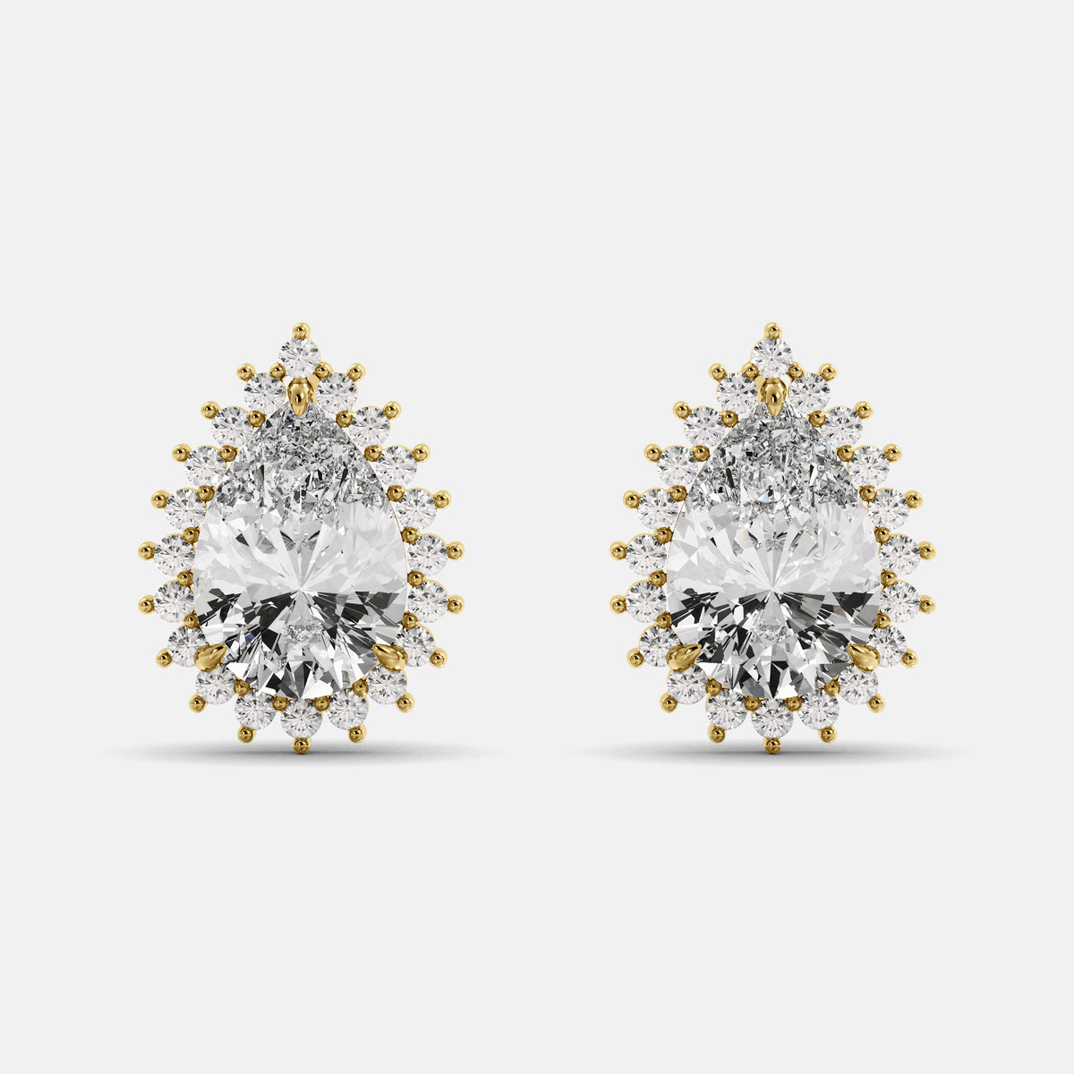 A pair of diamond emerald pear-cut halo stud earrings with gold accents on a white background.