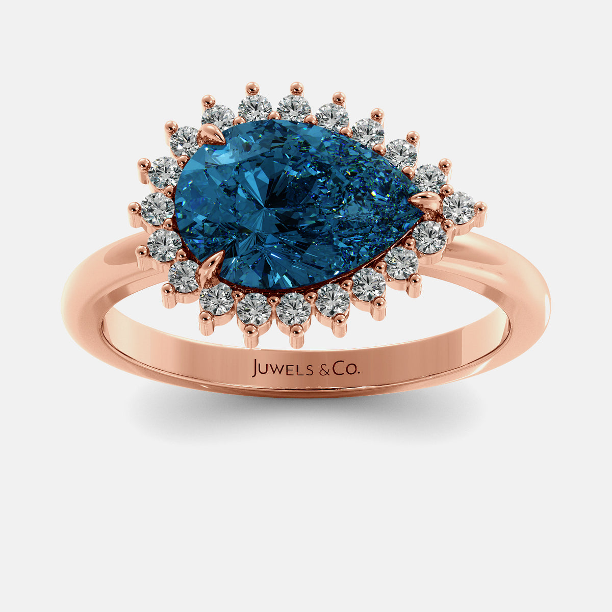 Rose gold ring with a blue gemstone and diamonds on a white background, branded 'Juwels & Co'.