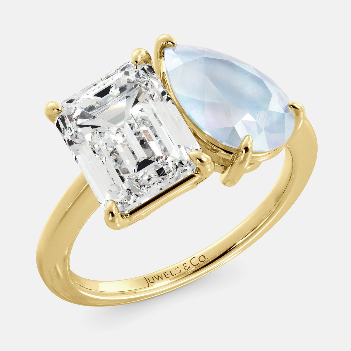 A toi et moi ring with an emerald-cut white topaz and a pear-cut gemstone. The emerald-cut morganite is set on the left of the ring, and the pear-cut gemstone is set on the right. The ring is made of recycled yellow gold and has a simple, elegant design. The pear-cut gemstone can be customized. **Here are some additional details about the image:** * The emerald-cut white topaz is a birthstone for April. * The pear-cut gemstone can be customized to any stone of your choice.