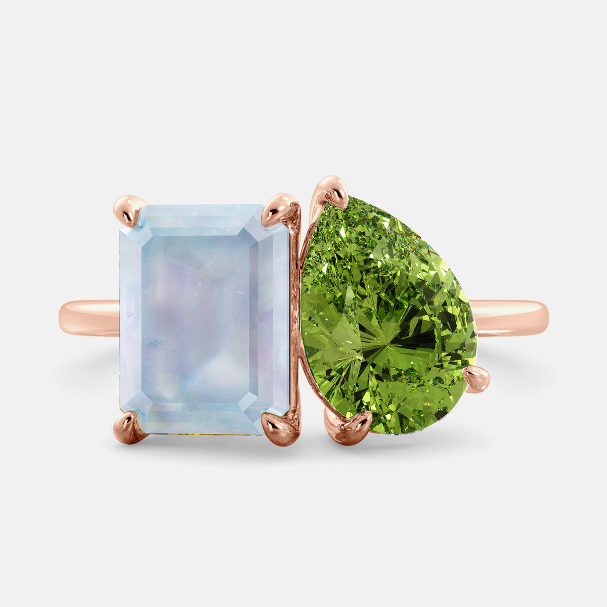 A gold ring featuring a rectangular blue moonstone on one side and a green pear-shaped gemstone on the other side.