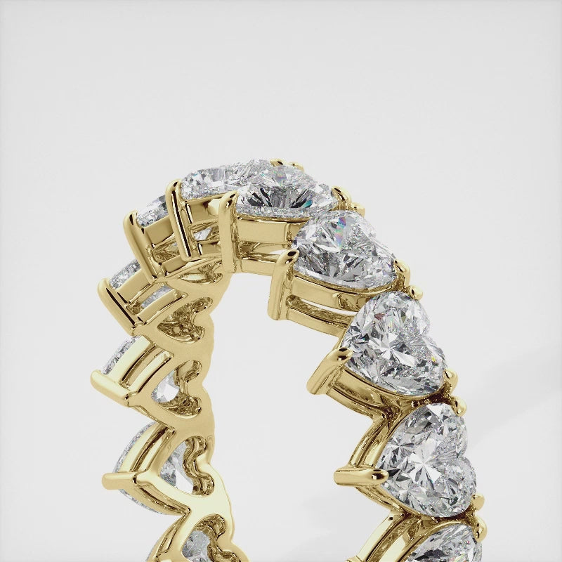 A close-up of a heart-shaped lab-grown diamond eternity wedding band in 14K yellow gold. The band is set with heart shape brilliant diamonds that sparkle and shine. The band is a beautiful and unique choice for a wedding band.