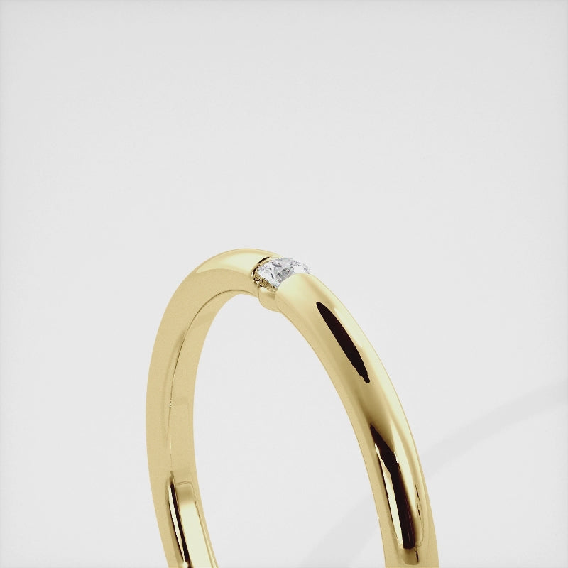 A close-up of a simple round wedding band in 14K yellow gold with a small round diamond in the center. The band is a classic and timeless design that is perfect for any occasion. The diamond is a beautiful accent that adds a touch of glamour.