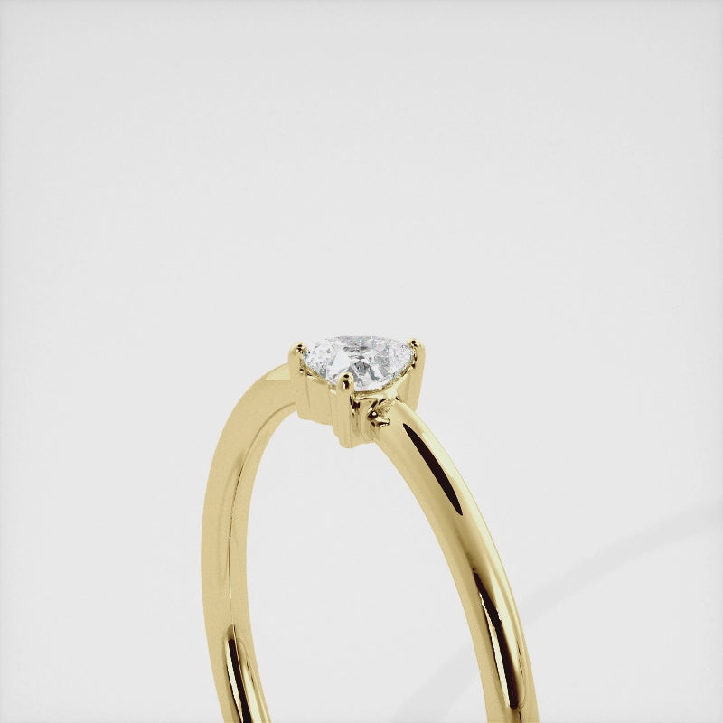 A close-up of a heart-shaped solitaire diamond ring in recycled yellow gold. The ring is set with a single, large diamond in the center of a heart-shaped setting. The ring is made of recycled yellow gold and has a simple, elegant design. The diamond is sparkling and reflects light beautifully. The ring is a perfect gift for a loved one or a special occasion.