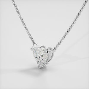 A close-up of a heart-shaped diamond necklace in recycled white gold. The necklace is set with a single heart-shaped diamond in the center of a pendant. The necklace is made of recycled white gold and has a simple, elegant design. The diamond is sparkling and reflects light beautifully. The necklace is a perfect gift for a loved one or a special occasion.