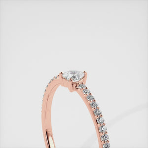 A close-up of a heart-shaped diamond ring with side stones in recycled rose gold. The ring is set with a single, large diamond in the center of a heart-shaped setting. The ring is made of recycled yellow gold and has a simple, elegant design. The diamond is sparkling and reflects light beautifully. The side stones are smaller diamonds that are set in the band of the ring. The ring is a perfect gift for a loved one or a special occasion.