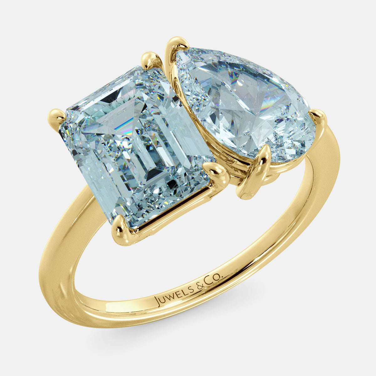 A toi et moi ring with an emerald-cut aquamarine and a pear-cut gemstone. The emerald-cut is set on the left of the ring, and the pear-cut gemstone is set on the right. The ring is made of recycled yellow gold and has a simple, elegant design. The pear-cut gemstone can be customized. **Here are some additional details about the image:** * The emerald-cut aquamarine is a birthstone for March. * The pear-cut gemstone can be customized to any stone of your choice.