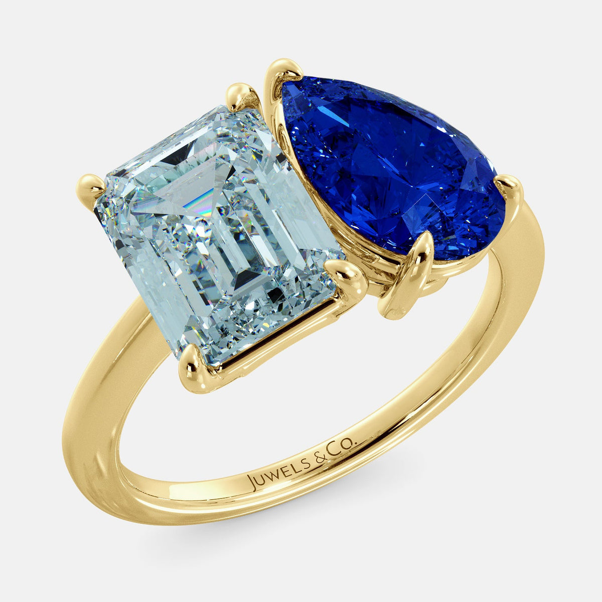 A toi et moi ring with an emerald-cut aquamarine and a pear-cut gemstone. The emerald-cut morganite is set on the left of the ring, and the pear-cut gemstone is set on the right. The ring is made of recycled yellow gold and has a simple, elegant design. The pear-cut gemstone can be customized. **Here are some additional details about the image:** * The emerald-cut aquamarine is a birthstone for March. * The pear-cut gemstone can be customized to any stone of your choice.