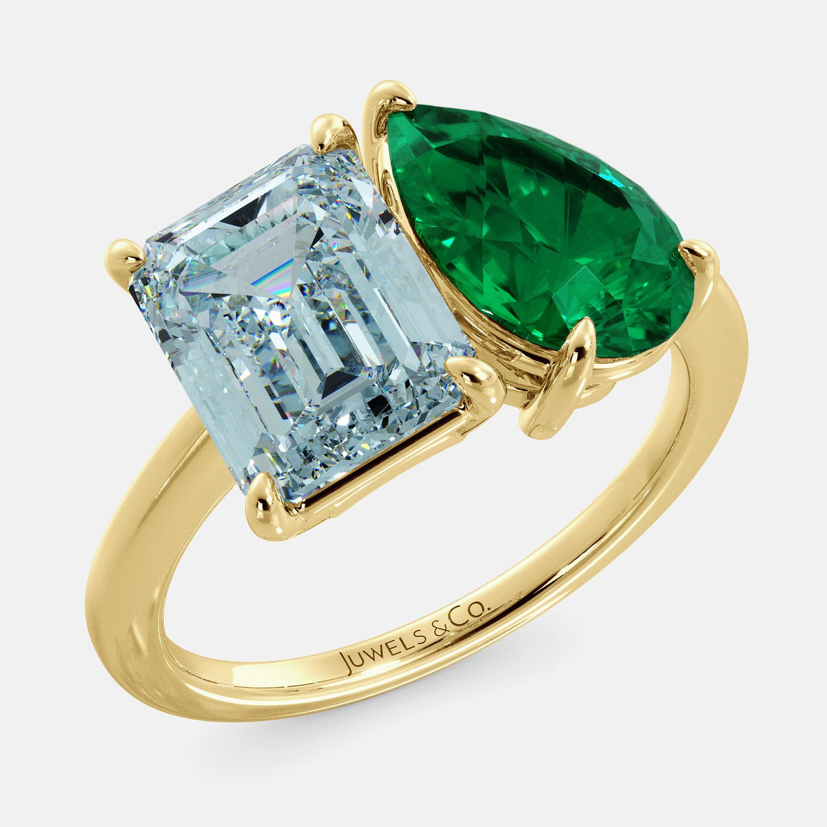 A toi et moi ring with an emerald-cut aquamarine and a pear-cut gemstone. The emerald-cut morganite is set on the left of the ring, and the pear-cut gemstone is set on the right. The ring is made of recycled yellow gold and has a simple, elegant design. The pear-cut gemstone can be customized. **Here are some additional details about the image:** * The emerald-cut aquamarine is a birthstone for March. * The pear-cut gemstone can be customized to any stone of your choice.