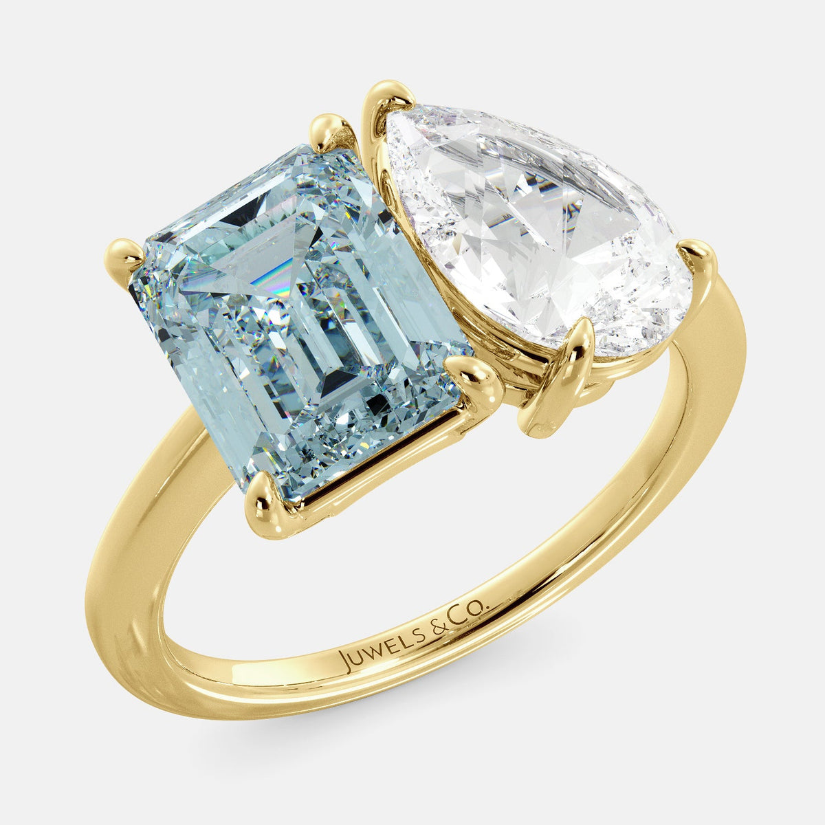A toi et moi ring with an emerald-cut aquamarine and a pear-cut gemstone. The emerald-cut morganite is set on the left of the ring, and the pear-cut gemstone is set on the right. The ring is made of recycled yellow gold and has a simple, elegant design. The pear-cut gemstone can be customized. **Here are some additional details about the image:** * The emerald-cut aquamarine is a birthstone for March. * The pear-cut gemstone can be customized to any stone of your choice.
