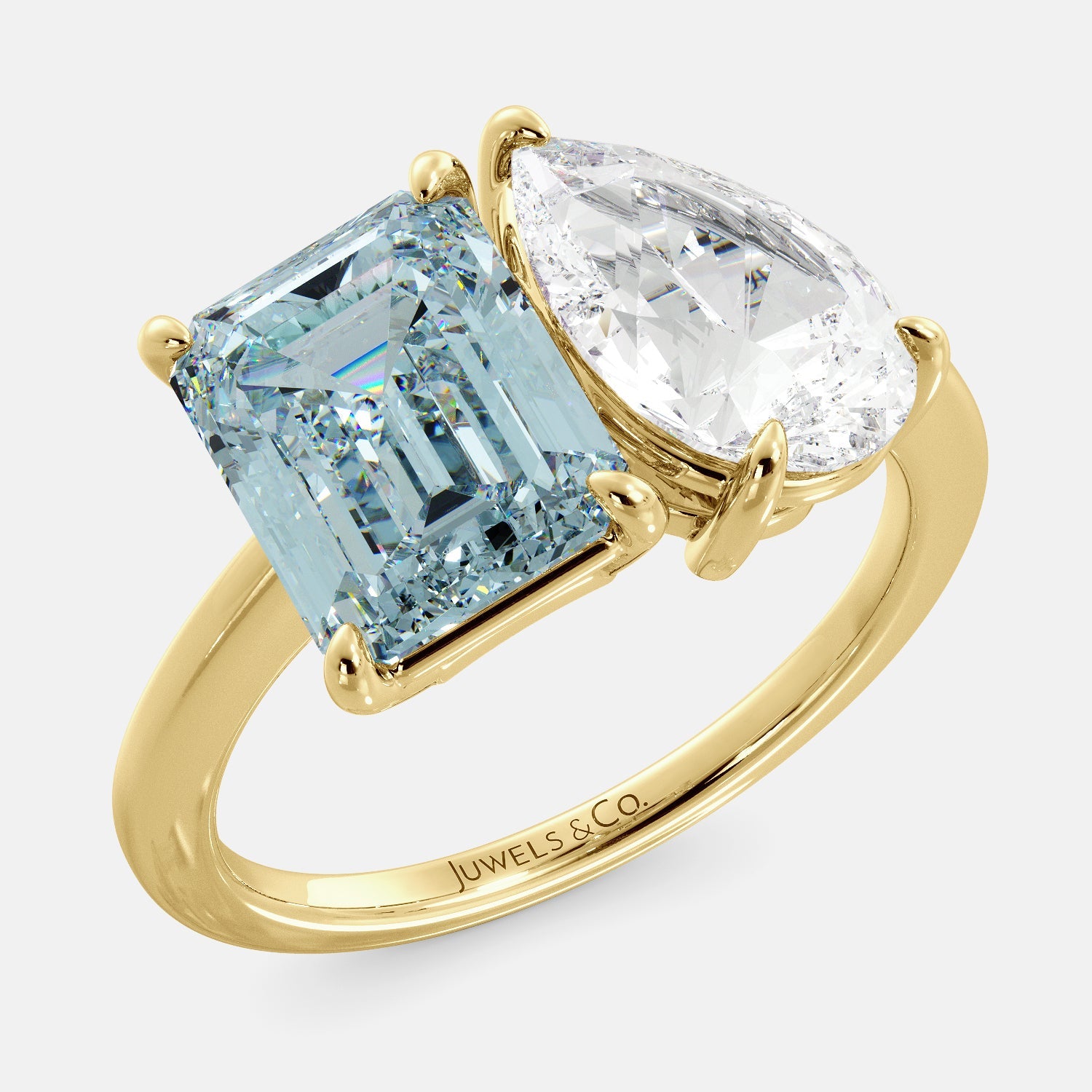 A toi et moi ring with an emerald-cut aquamarine and a pear-cut gemstone. The emerald-cut morganite is set on the left of the ring, and the pear-cut gemstone is set on the right. The ring is made of recycled yellow gold and has a simple, elegant design. The pear-cut gemstone can be customized. **Here are some additional details about the image:** * The emerald-cut aquamarine is a birthstone for March. * The pear-cut gemstone can be customized to any stone of your choice.