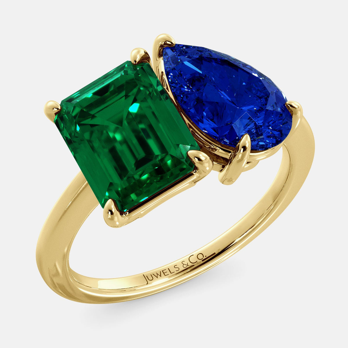 A toi et moi ring with an emerald-cut emerald and a pear-cut gemstone. The emerald-cut morganite is set on the left of the ring, and the pear-cut gemstone is set on the right. The ring is made of recycled yellow gold and has a simple, elegant design. The pear-cut gemstone can be customized. **Here are some additional details about the image:** * The emerald-cut white emerald is a birthstone for May. * The pear-cut gemstone can be customized to any stone of your choice.