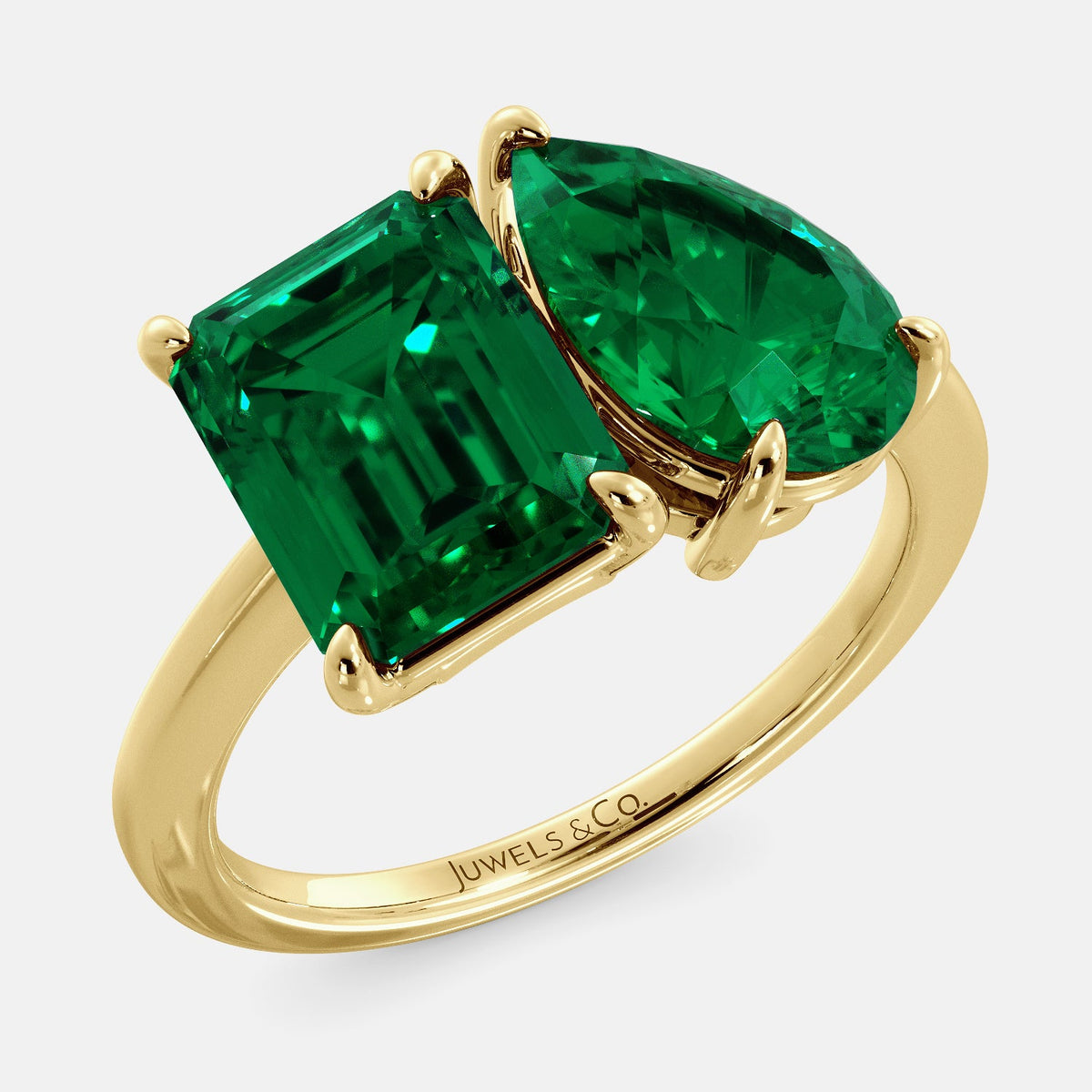 A toi et moi ring with an emerald-cut emerald and a pear-cut gemstone. The emerald-cut morganite is set on the left of the ring, and the pear-cut gemstone is set on the right. The ring is made of recycled yellow gold and has a simple, elegant design. The pear-cut gemstone can be customized. **Here are some additional details about the image:** * The emerald-cut white emerald is a birthstone for May. * The pear-cut gemstone can be customized to any stone of your choice.