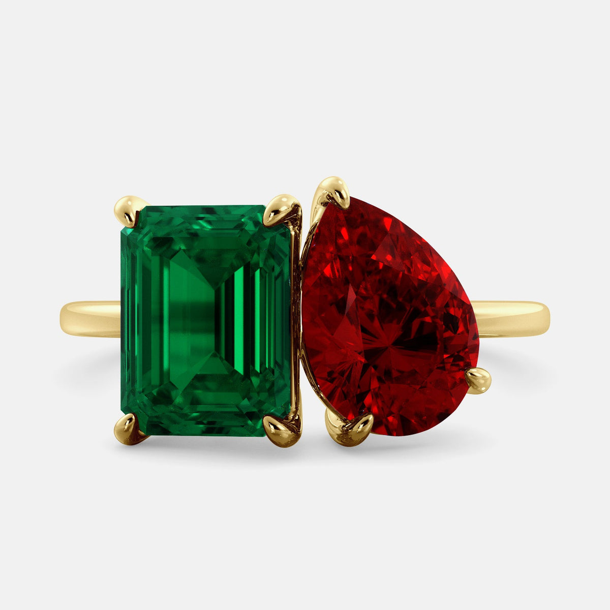 A toi et moi ring with an emerald-cut emerald and a pear-cut gemstone. The emerald-cut morganite is set on the left of the ring, and the pear-cut gemstone is set on the right. The ring is made of recycled yellow gold and has a simple, elegant design. The pear-cut gemstone can be customized. **Here are some additional details about the image:** * The emerald-cut white emerald is a birthstone for May. * The pear-cut gemstone can be customized to any stone of your choice.