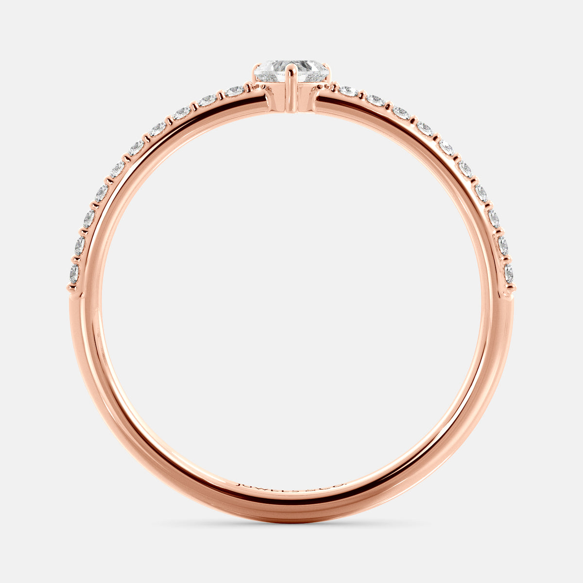 A close-up of a heart-shaped diamond ring with side stones in recycled rose gold. The ring is set with a single, large diamond in the center of a heart-shaped setting. The ring is made of recycled yellow gold and has a simple, elegant design. The diamond is sparkling and reflects light beautifully. The side stones are smaller diamonds that are set in the band of the ring. The ring is a perfect gift for a loved one or a special occasion.