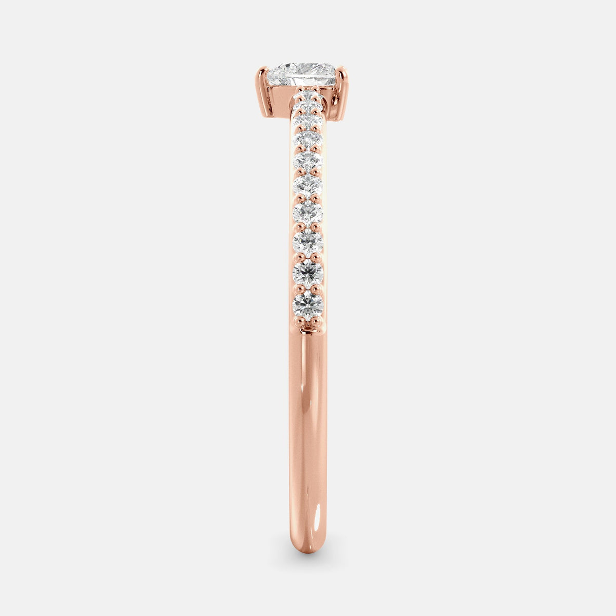 A close-up of a heart-shaped diamond ring with side stones in recycled rose gold. The ring is set with a single, large diamond in the center of a heart-shaped setting. The ring is made of recycled yellow gold and has a simple, elegant design. The diamond is sparkling and reflects light beautifully. The side stones are smaller diamonds that are set in the band of the ring. The ring is a perfect gift for a loved one or a special occasion.