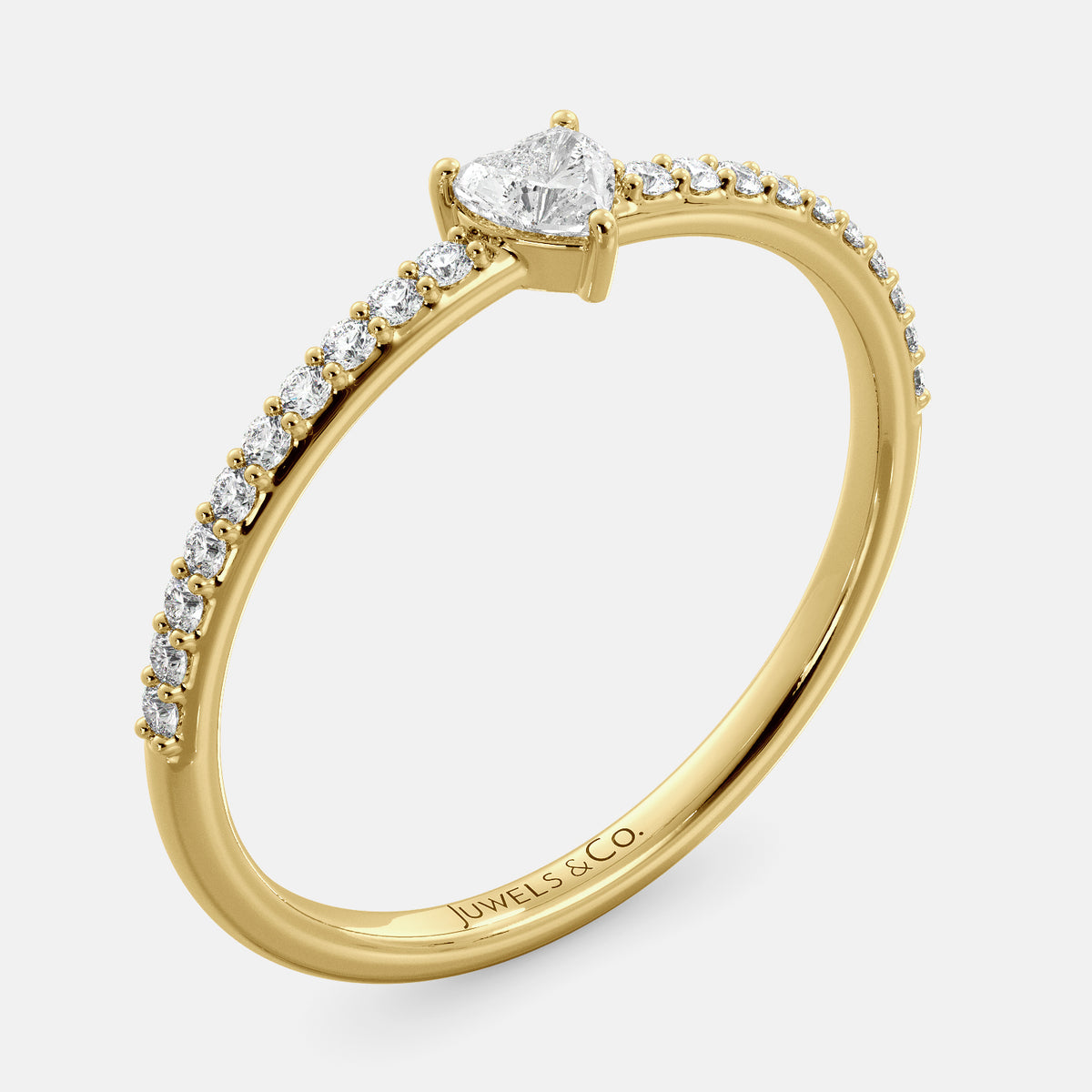 A close-up of a heart-shaped diamond ring with side stones in recycled yellow gold. The ring is set with a single, large diamond in the center of a heart-shaped setting. The ring is made of recycled yellow gold and has a simple, elegant design. The diamond is sparkling and reflects light beautifully. The side stones are smaller diamonds that are set in the band of the ring. The ring is a perfect gift for a loved one or a special occasion.