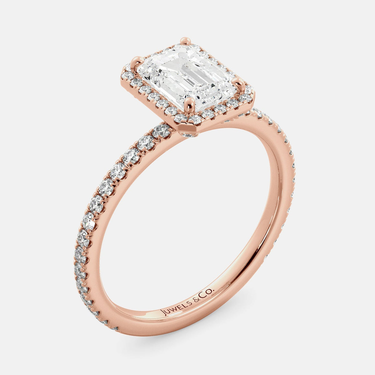 This image shows a stunning emerald halo lab-grown diamond ring with pavé on a rose gold band. The ring features a 1.5-carat emerald-cut lab-grown diamond in the center, surrounded by a halo of smaller lab-grown diamonds. The ring is made of 14k rose gold and is available in a variety of sizes.