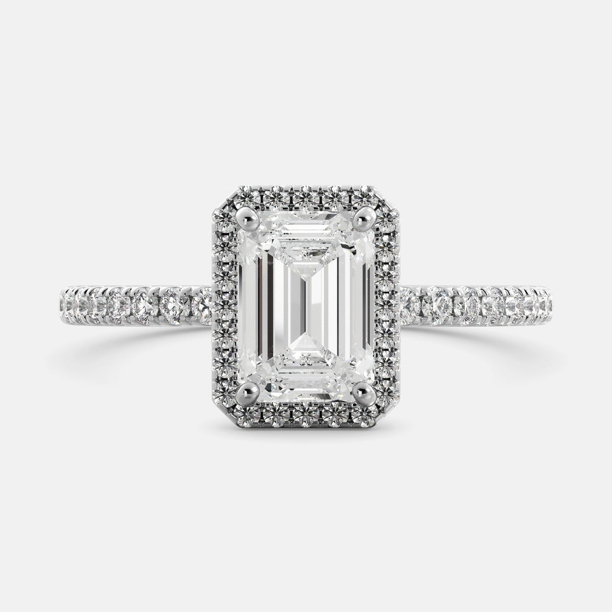 This image shows a stunning emerald halo lab-grown diamond ring with pavé on a white gold band. The ring features a 1.5-carat emerald-cut lab-grown diamond in the center, surrounded by a halo of smaller lab-grown diamonds. The ring is made of 14k white gold and is available in a variety of sizes.