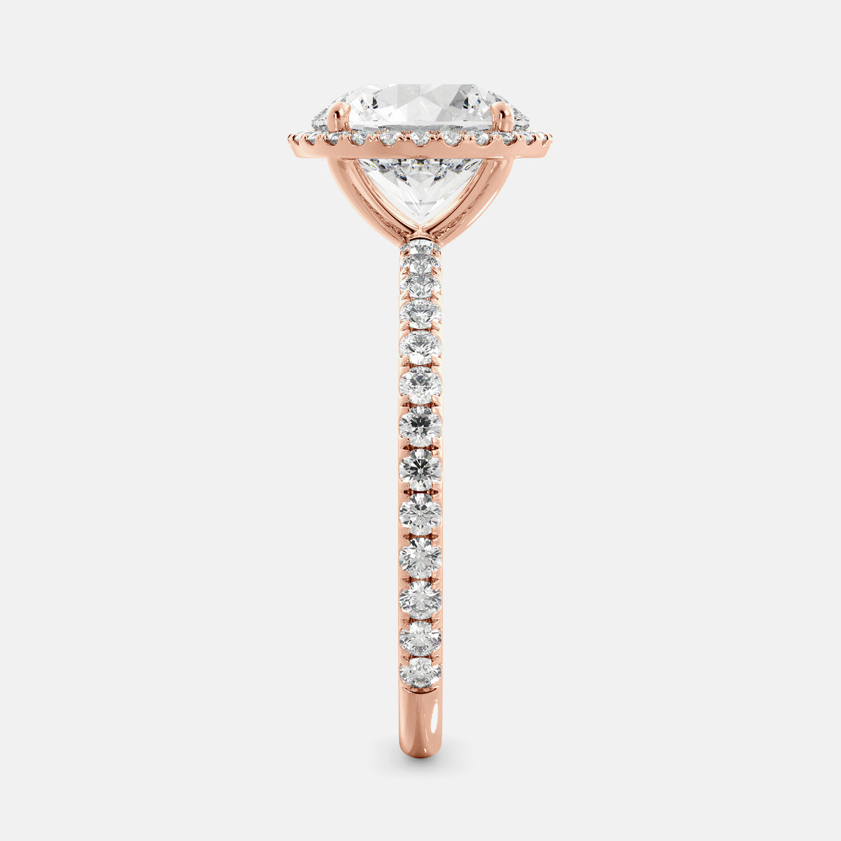 This image shows a beautiful round halo lab-diamond ring with pavé on a rose gold band. The ring features a round brilliant-cut lab-diamond in the center, surrounded by a halo of smaller diamonds. The band is pavé-set with smaller diamonds, creating a sparkling and elegant look. The ring is made of 14k rose gold and is available in a variety of sizes.