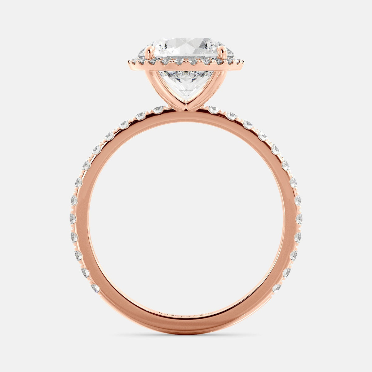 This image shows a beautiful round halo lab-diamond ring with pavé on a rose gold band. The ring features a round brilliant-cut lab-diamond in the center, surrounded by a halo of smaller diamonds. The band is pavé-set with smaller diamonds, creating a sparkling and elegant look. The ring is made of 14k rose gold and is available in a variety of sizes.