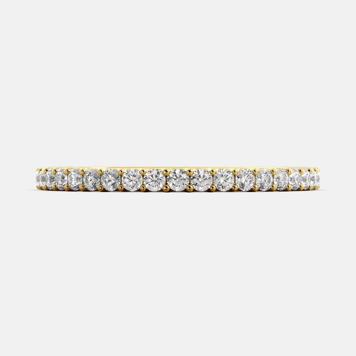 A close-up of a yellow gold eternity wedding band with a row of round diamonds. The band is a classic and timeless design that is perfect for any occasion. The diamonds sparkle and shine, adding a touch of glamour. The band is made of 14K yellow gold and features lab-grown diamonds that are conflict-free.