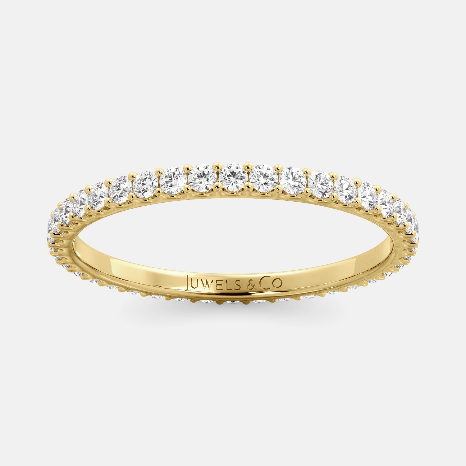 A close-up of a yellow gold eternity wedding band with a row of round diamonds. The band is a classic and timeless design that is perfect for any occasion. The diamonds sparkle and shine, adding a touch of glamour. The band is made of 14K yellow gold and features lab-grown diamonds that are conflict-free.