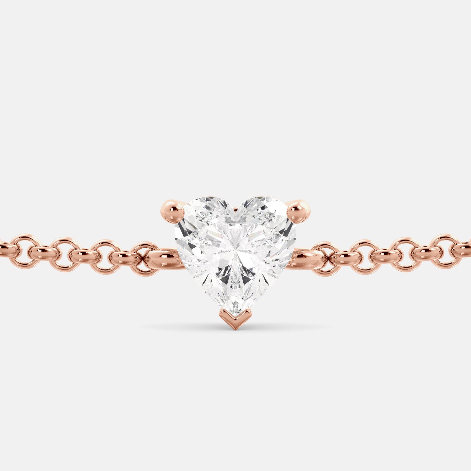 A close-up of a heart-shaped diamond bracelet in recycled rose gold. The bracelet is set with a single, large diamond in the center of a heart-shaped pendant. The bracelet is made of recycled rose gold and has a simple, elegant design. The diamond is sparkling and reflects light beautifully. The bracelet is a perfect gift for a loved one or a special occasion.