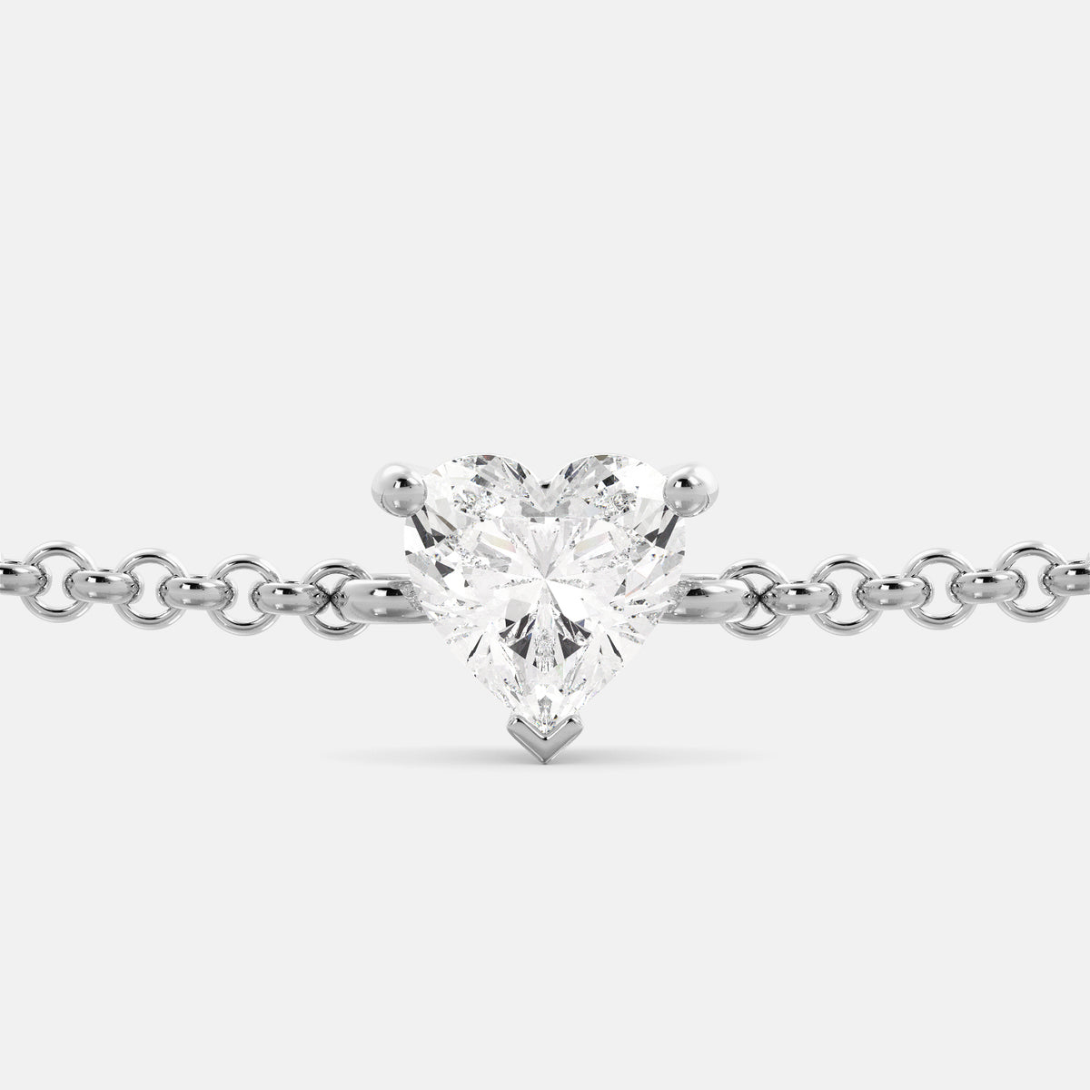 A close-up of a heart-shaped diamond bracelet in recycled white gold. The bracelet is set with a single, large diamond in the center of a heart-shaped pendant. The bracelet is made of recycled white gold and has a simple, elegant design. The diamond is sparkling and reflects light beautifully. The bracelet is a perfect gift for a loved one or a special occasion.