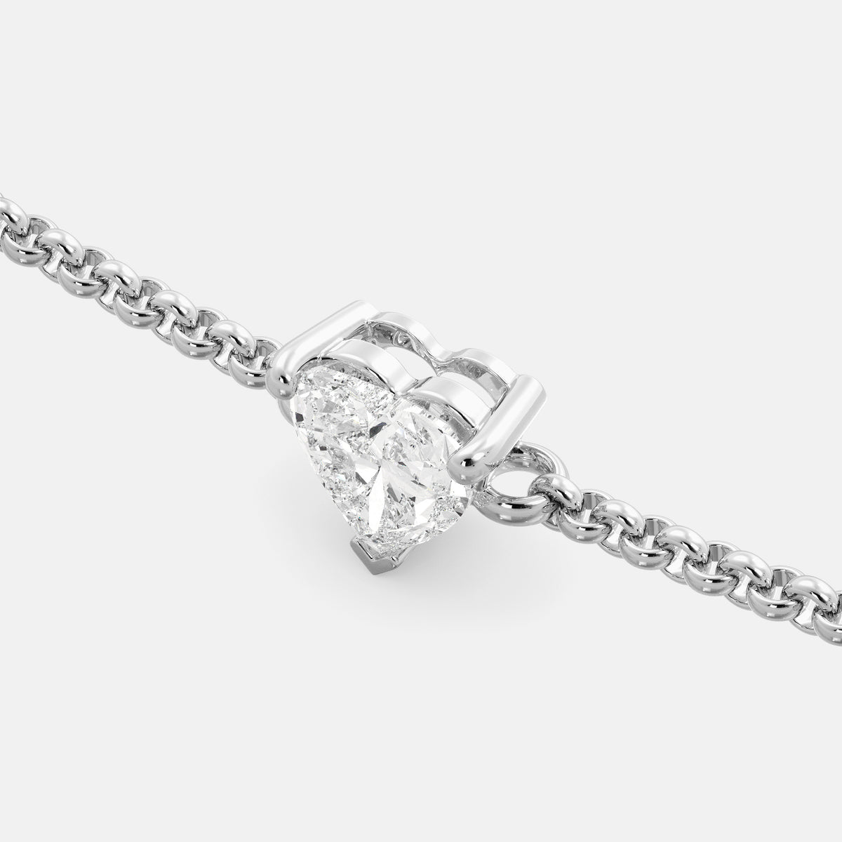 A close-up of a heart-shaped diamond bracelet in recycled white gold. The bracelet is set with a single, large diamond in the center of a heart-shaped pendant. The bracelet is made of recycled white gold and has a simple, elegant design. The diamond is sparkling and reflects light beautifully. The bracelet is a perfect gift for a loved one or a special occasion.