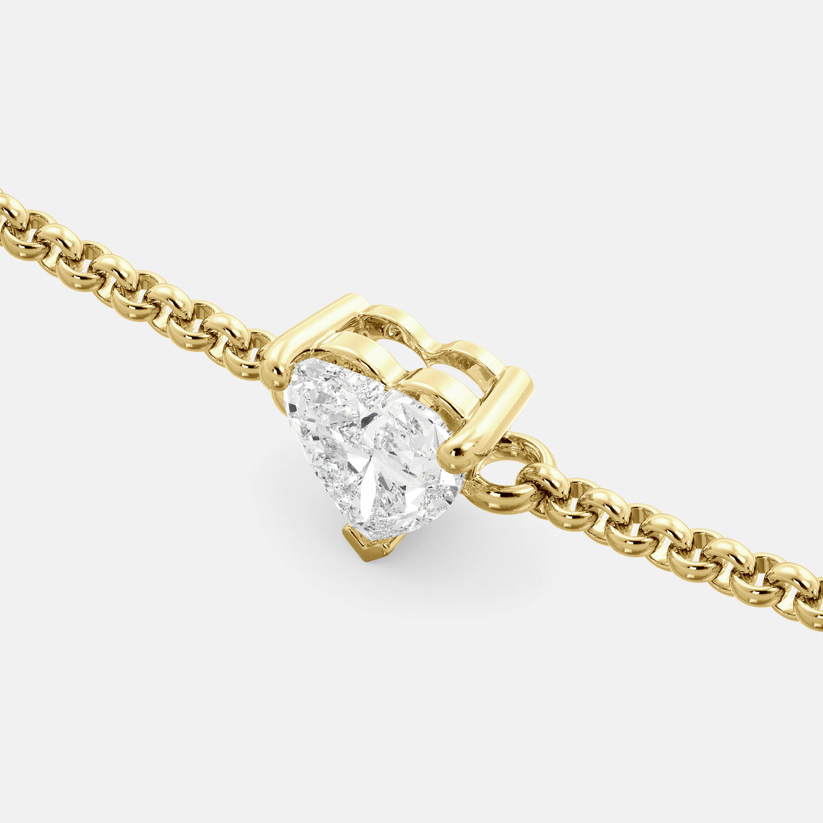 A close-up of a heart-shaped diamond bracelet in recycled yellow gold. The bracelet is set with a single, large diamond in the center of a heart-shaped pendant. The bracelet is made of recycled yellow gold and has a simple, elegant design. The diamond is sparkling and reflects light beautifully. The bracelet is a perfect gift for a loved one or a special occasion.