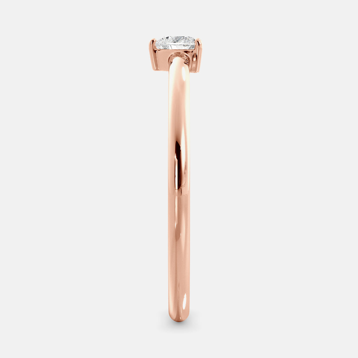 A close-up of a heart-shaped solitaire diamond ring in recycled rose gold. The ring is set with a single, large diamond in the center of a heart-shaped setting. The ring is made of recycled rose gold and has a simple, elegant design. The diamond is sparkling and reflects light beautifully. The ring is a perfect gift for a loved one or a special occasion.